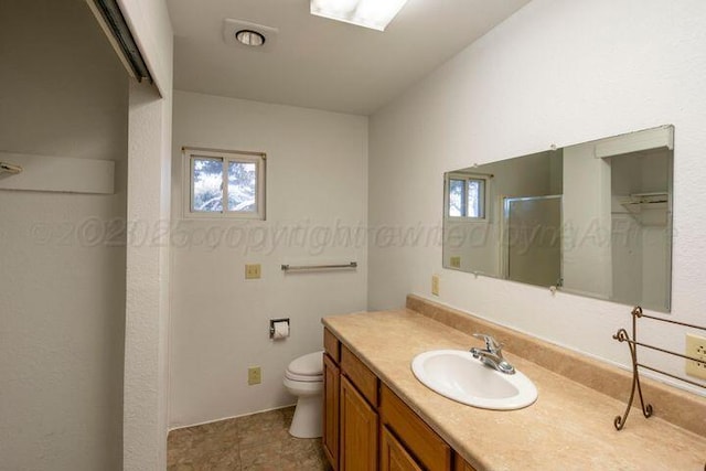 bathroom featuring toilet, an enclosed shower, and vanity