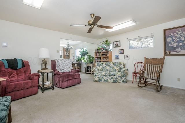 carpeted living room with ceiling fan with notable chandelier