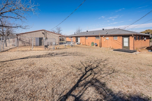 back of house with a gate, brick siding, and fence