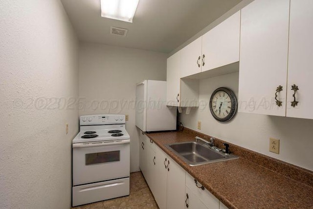 kitchen featuring white range with electric cooktop, dark countertops, visible vents, white cabinets, and a sink