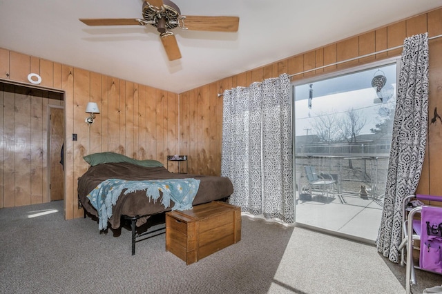 carpeted bedroom featuring wooden walls and a ceiling fan