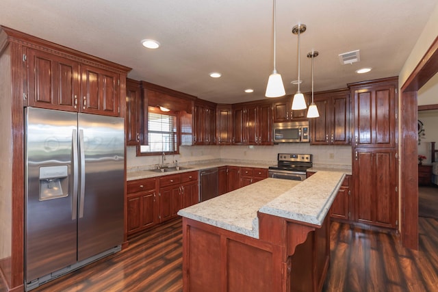 kitchen featuring stainless steel appliances, dark hardwood / wood-style flooring, a center island, hanging light fixtures, and sink