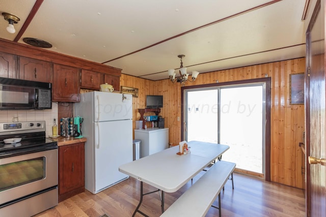 kitchen featuring backsplash, wooden walls, white fridge, and electric range