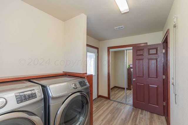 laundry area with light hardwood / wood-style flooring and washing machine and dryer