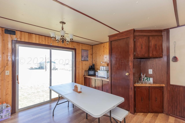 dining space featuring wood walls, light hardwood / wood-style floors, and a chandelier