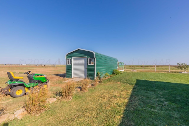 view of outbuilding with a lawn and a rural view