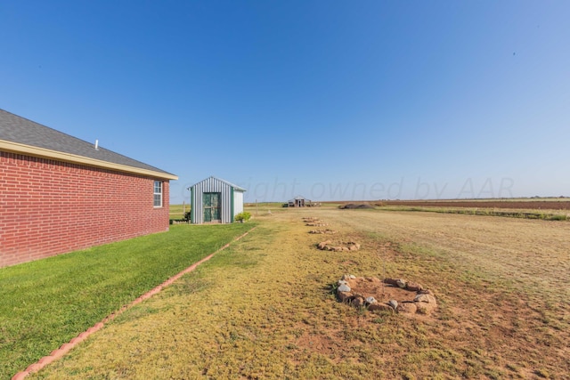 view of yard featuring a storage shed and a rural view