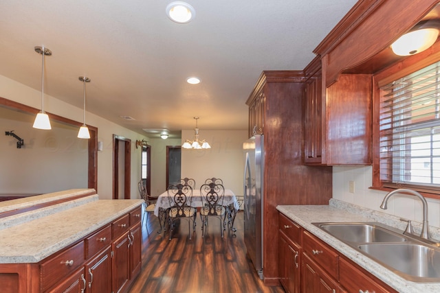 kitchen featuring dark hardwood / wood-style flooring, a notable chandelier, sink, stainless steel refrigerator, and decorative light fixtures