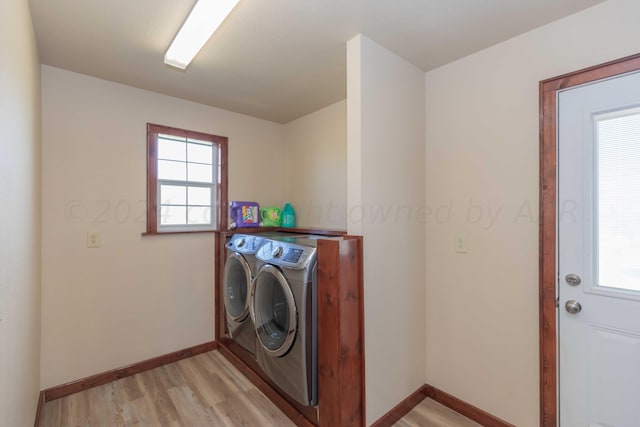 laundry area with a wealth of natural light, separate washer and dryer, and light hardwood / wood-style floors