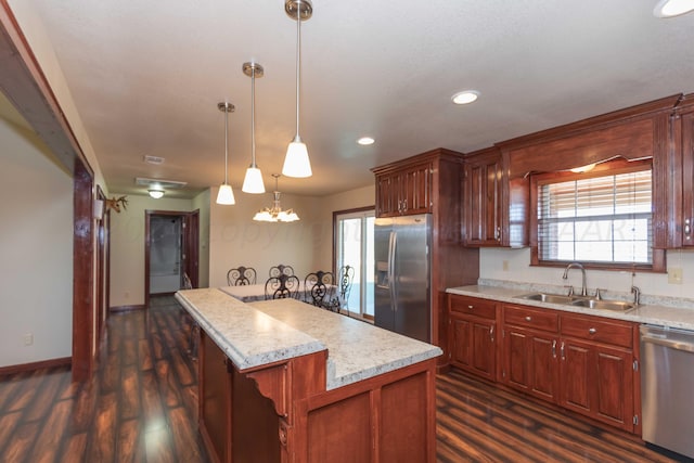 kitchen with dark wood-type flooring, light stone counters, sink, pendant lighting, and appliances with stainless steel finishes