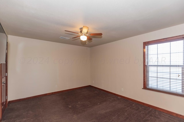 spare room with ceiling fan and dark carpet