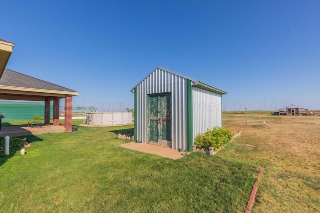 view of outbuilding featuring a water view, a lawn, and a pool