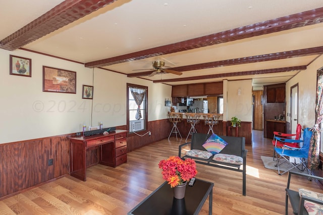 living room featuring beamed ceiling, ceiling fan, wood walls, and light hardwood / wood-style flooring