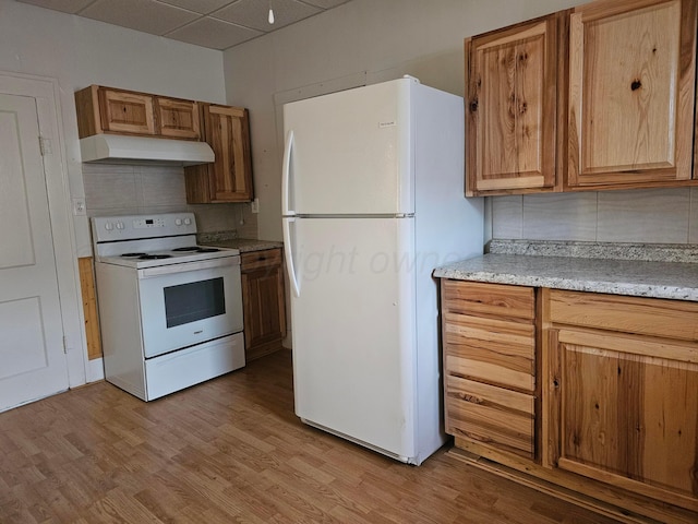 kitchen featuring light stone counters, a paneled ceiling, light wood-type flooring, white appliances, and backsplash