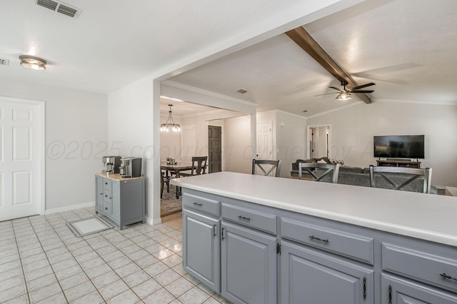 kitchen featuring ceiling fan with notable chandelier, lofted ceiling with beams, crown molding, gray cabinets, and light tile patterned flooring