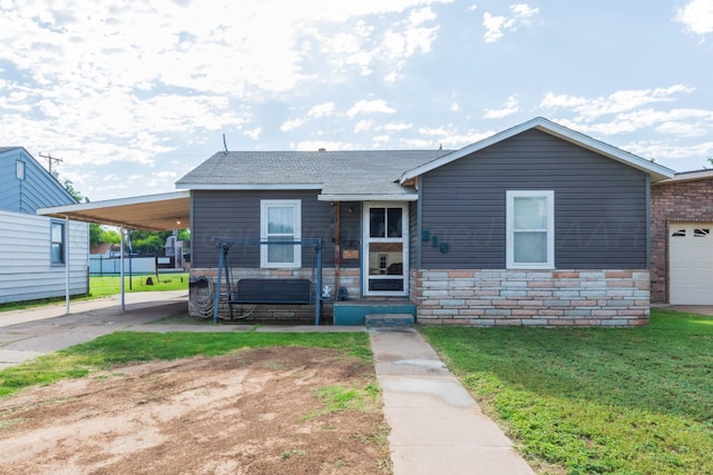210 Oak Ave, Dumas, TX 79029 - view of front of property with a front lawn, driveway, stone siding, an attached carport, and a shingled roof