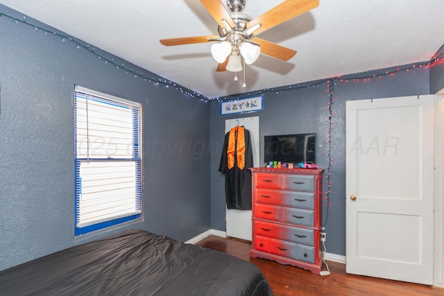 210 Oak Ave, Dumas, TX 79029 - bedroom with wood finished floors, a textured wall, and a ceiling fan