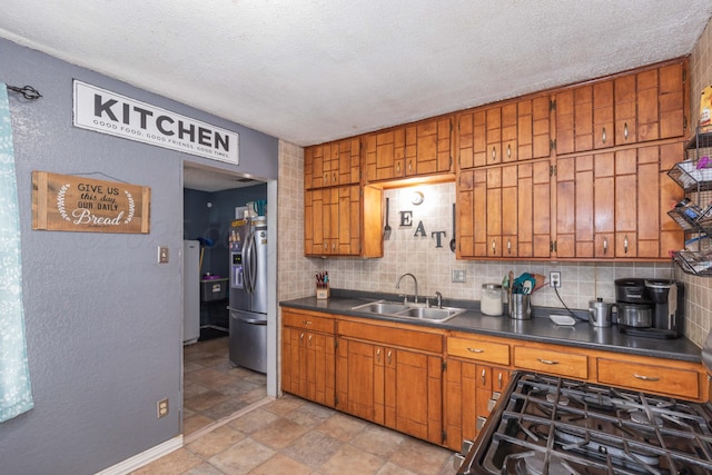 210 Oak Ave, Dumas, TX 79029 - kitchen featuring stainless steel fridge, dark countertops, brown cabinets, tasteful backsplash, and a textured ceiling