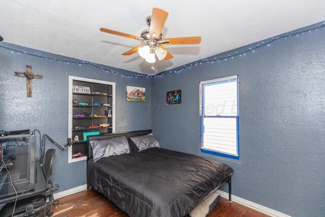 210 Oak Ave, Dumas, TX 79029 - bedroom with wood finished floors, a textured wall, and a ceiling fan