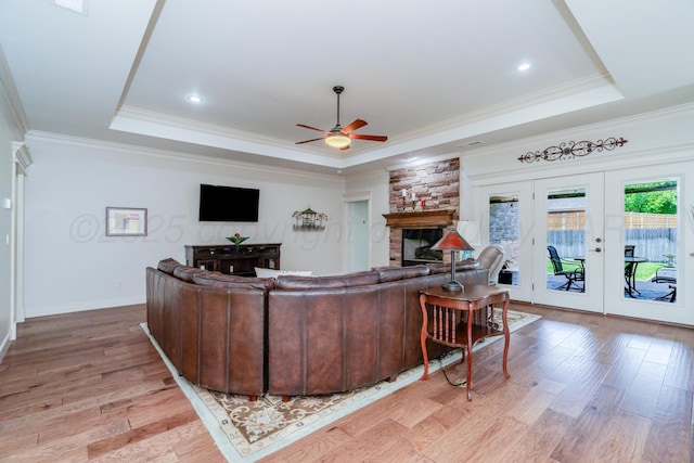 7601 Continental Pkwy, Amarillo, TX 79119 - living area with a tray ceiling, a ceiling fan, a stone fireplace, light wood-style flooring, and crown molding