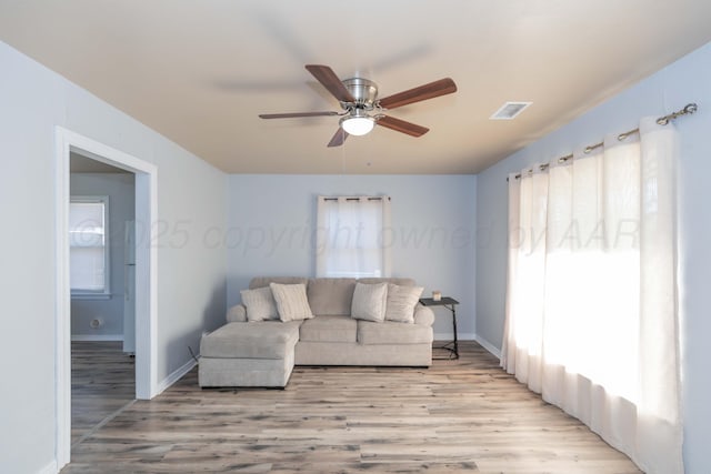 living area with ceiling fan, baseboards, visible vents, and light wood-style flooring