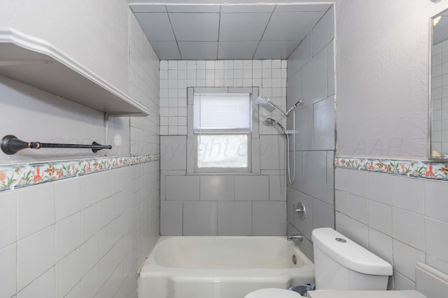 bathroom featuring toilet, shower / tub combination, and tile walls