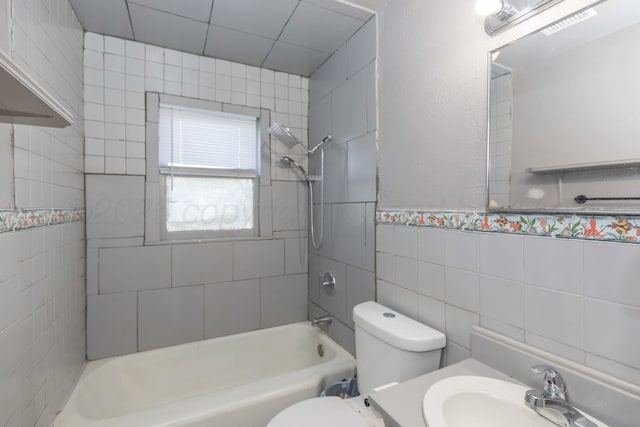 bathroom with tile walls, shower / bathing tub combination, a sink, and toilet