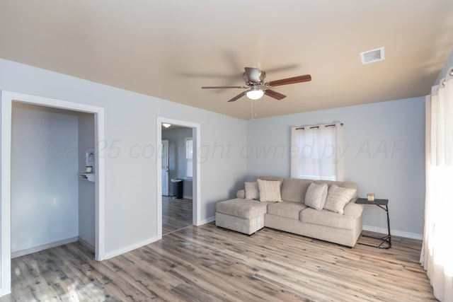 living area featuring wood finished floors, visible vents, baseboards, and ceiling fan