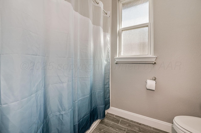 bathroom with toilet and a shower with shower curtain