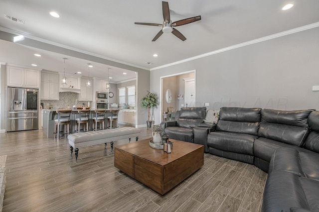 living room featuring hardwood / wood-style flooring, ornamental molding, and ceiling fan