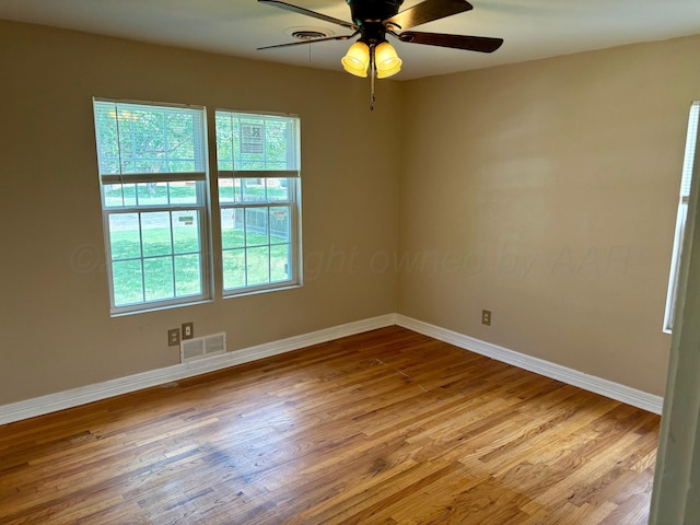 unfurnished room featuring plenty of natural light, a ceiling fan, baseboards, and wood finished floors