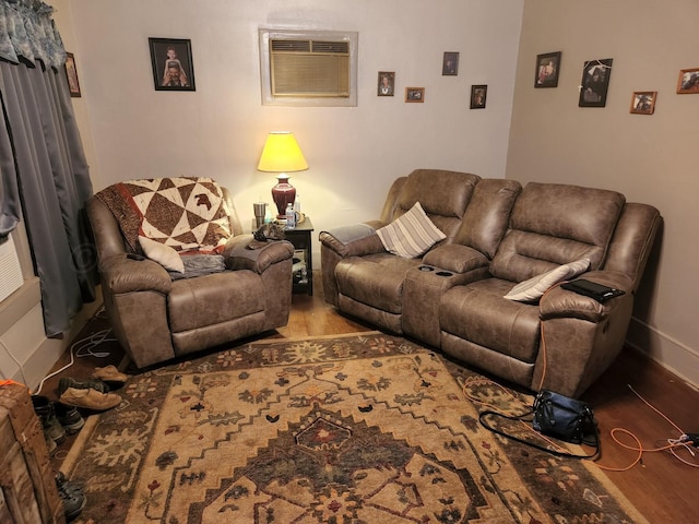living area with a wall mounted AC, wood finished floors, and baseboards