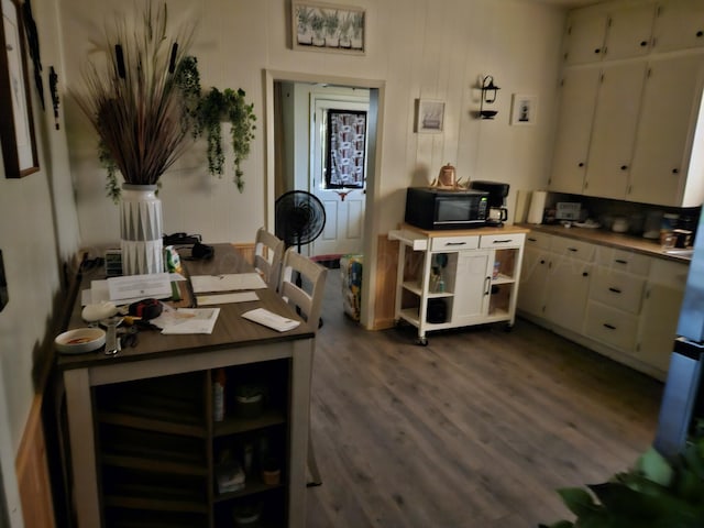 kitchen featuring black microwave, dark wood-style flooring, white cabinets, and light countertops