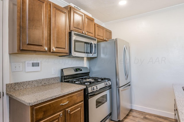kitchen featuring brown cabinets, stainless steel appliances, baseboards, light wood-type flooring, and ornamental molding