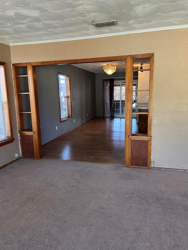 unfurnished room with dark wood-type flooring, a chandelier, and crown molding