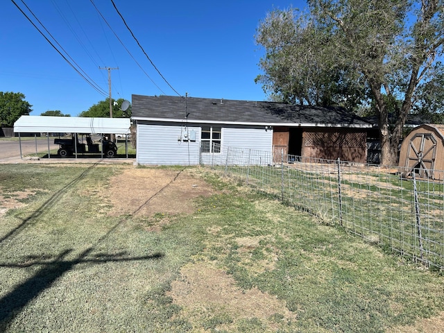 rear view of house featuring fence, a storage shed, an outdoor structure, a yard, and a carport