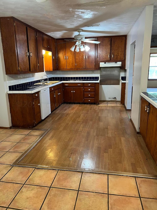 kitchen featuring sink, decorative backsplash, white dishwasher, and light hardwood / wood-style flooring