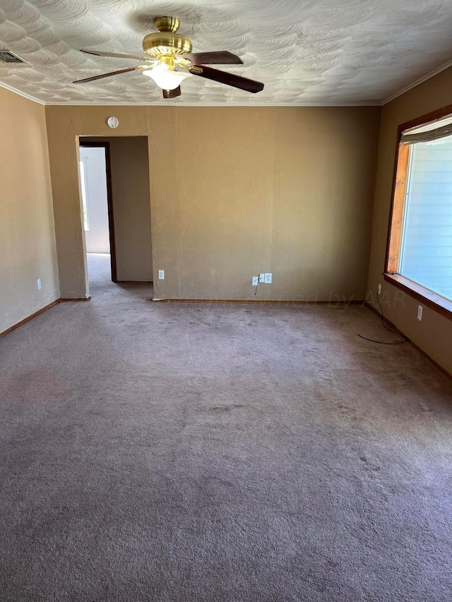 unfurnished room featuring ornamental molding, carpet, a textured ceiling, and ceiling fan