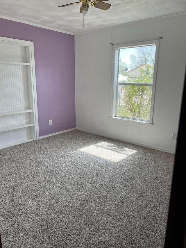 spare room featuring carpet floors, a textured ceiling, baseboards, and ceiling fan