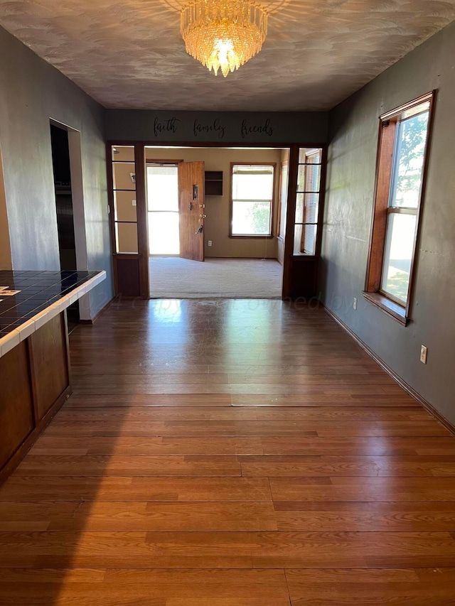 interior space featuring light wood-type flooring, a notable chandelier, and a healthy amount of sunlight