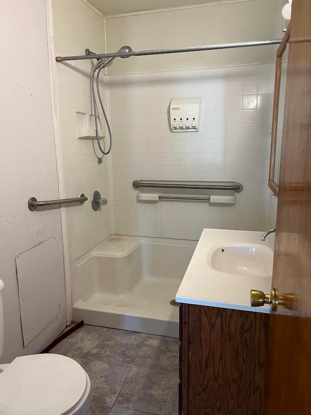 bathroom with toilet, vanity, and a tile shower