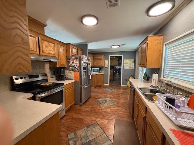 1228 S Osborne St, Pampa, TX 79065 - kitchen featuring stainless steel appliances, under cabinet range hood, a sink, brown cabinets, and light countertops