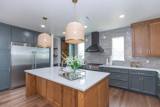 9504 Stonecrest Dr, Amarillo, TX 79118 - kitchen with stainless steel appliances, wall chimney range hood, light countertops, decorative backsplash, and wood finished floors