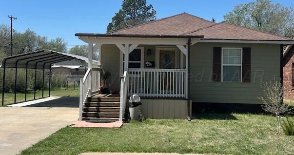 bungalow-style home with concrete driveway, a detached carport, a shingled roof, a front yard, and a porch