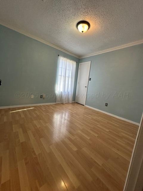 empty room featuring crown molding, a textured ceiling, baseboards, and light wood-style floors