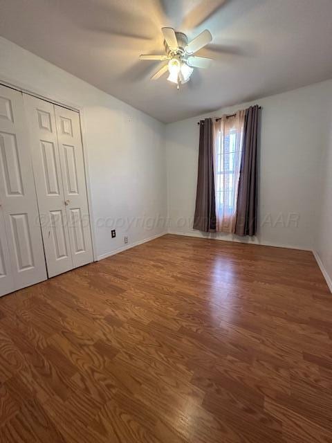 unfurnished bedroom with a ceiling fan, wood finished floors, and baseboards