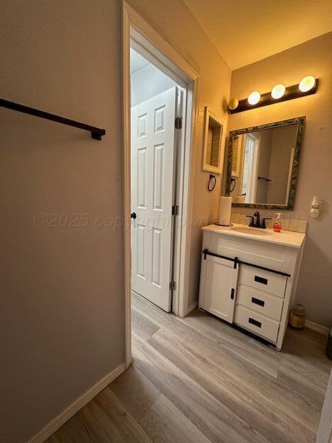 bathroom featuring vanity, wood finished floors, and baseboards