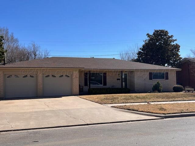 ranch-style home with concrete driveway, brick siding, an attached garage, and roof with shingles