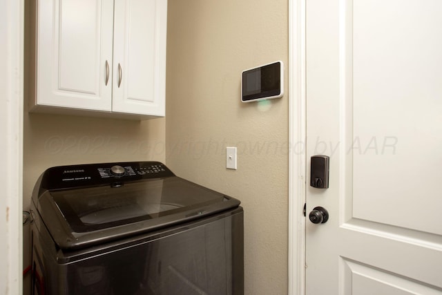 clothes washing area featuring washer / dryer and cabinet space