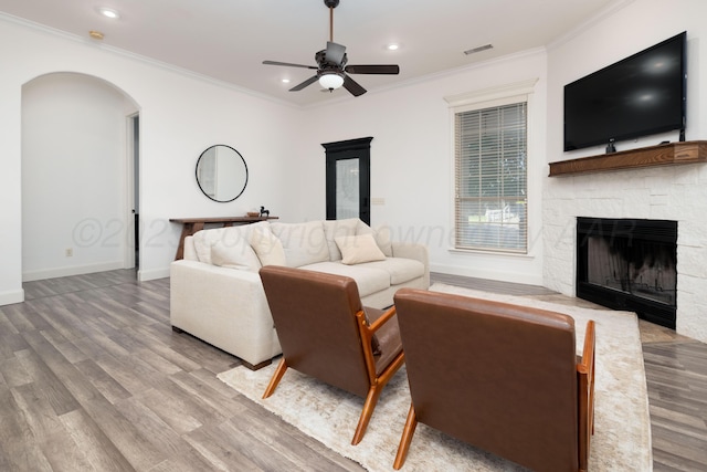 8603 Garden Way Dr, Amarillo, TX 79119 - living area with wood finished floors, a fireplace, ornamental molding, a ceiling fan, and arched walkways